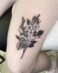 a black and white tattoo of flowers on a woman's thigh