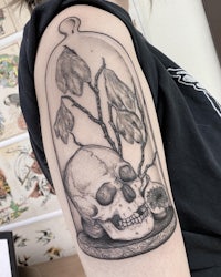a black and white tattoo of a skull in a glass jar