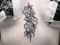 a tattoo of a knife with flowers on it