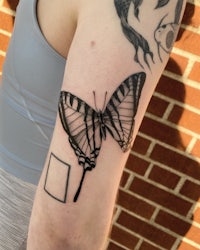 a black and white butterfly tattoo on a woman's arm