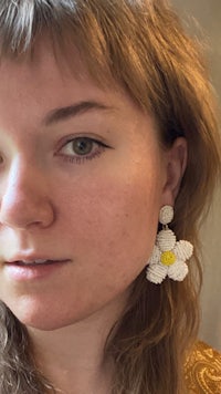 a woman wearing a flower shaped beaded earring