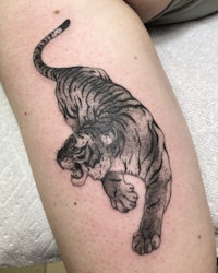 a tiger tattoo on a woman's thigh
