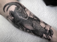 a black and white goat tattoo on the forearm