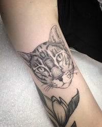 a black and white cat tattoo on a woman's arm