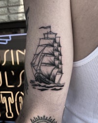a tattoo of a sailing ship on a man's arm