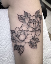 a black and white flower tattoo on a woman's thigh