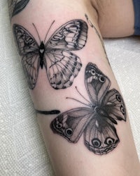 two black and white butterfly tattoos on a woman's thigh