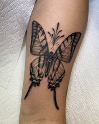a black and white butterfly tattoo on the forearm