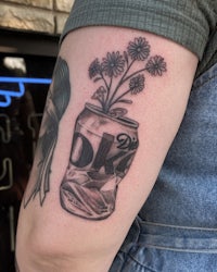 a tattoo of a coke can with flowers in it