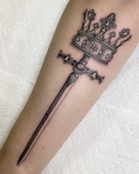 a tattoo of a sword with a crown on it