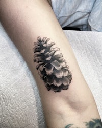 a black and white tattoo of a pine cone